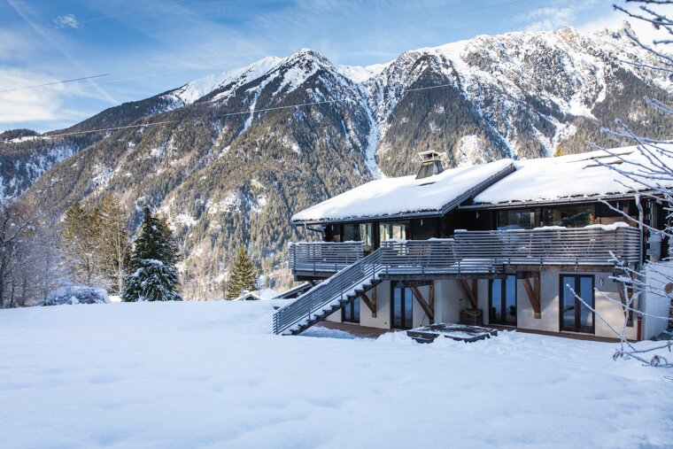 A snow covered house with mountains in the background