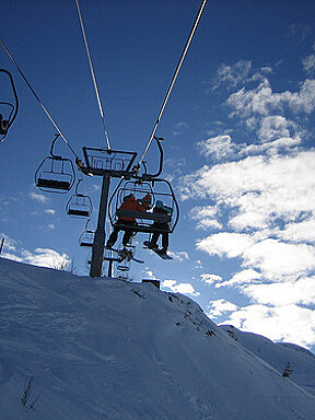 Skiers on a ski lift with a blue sky in the background