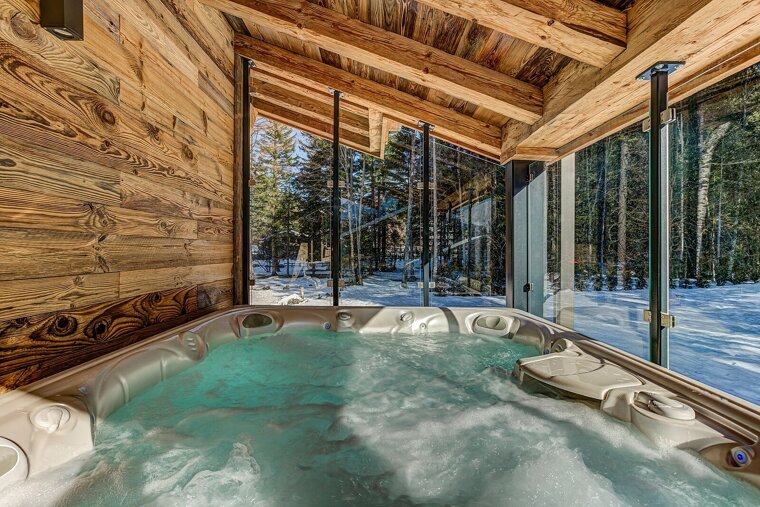 A hot tub with a view of a snowy forest